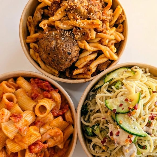 Three bowls of pasta: rigatoni with red sauce, spaghetti with zucchini, and cavatappi with meatballs.