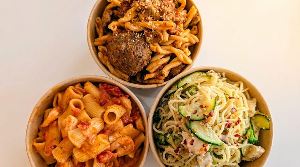 Three bowls of pasta: rigatoni with red sauce, spaghetti with zucchini, and cavatappi with meatballs.